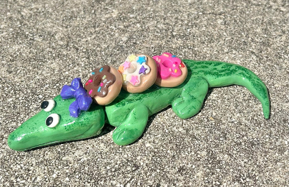 Sculpted alligator figurine with donuts