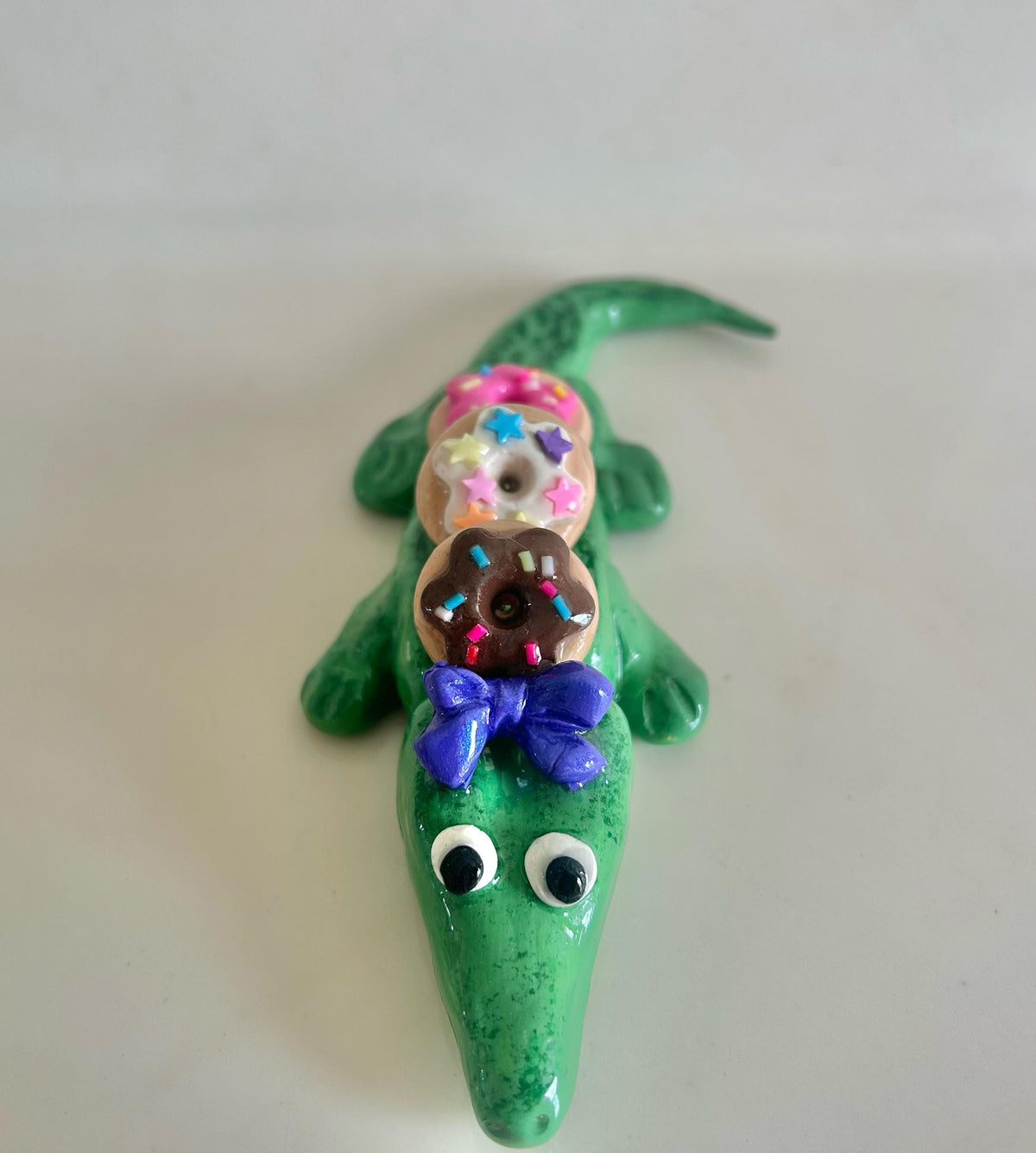 Sculpted alligator figurine with donuts