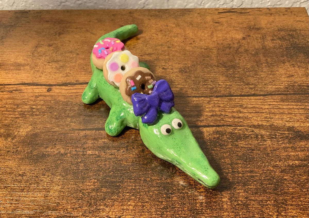 Sculpted alligator figurine with donuts