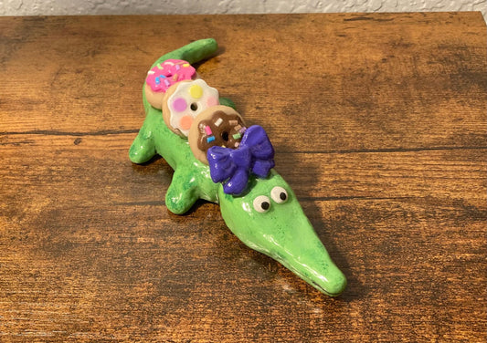 Sculpted alligator figurine with donuts