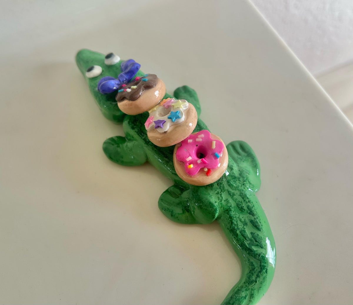 Sculpted alligator figurine with donuts