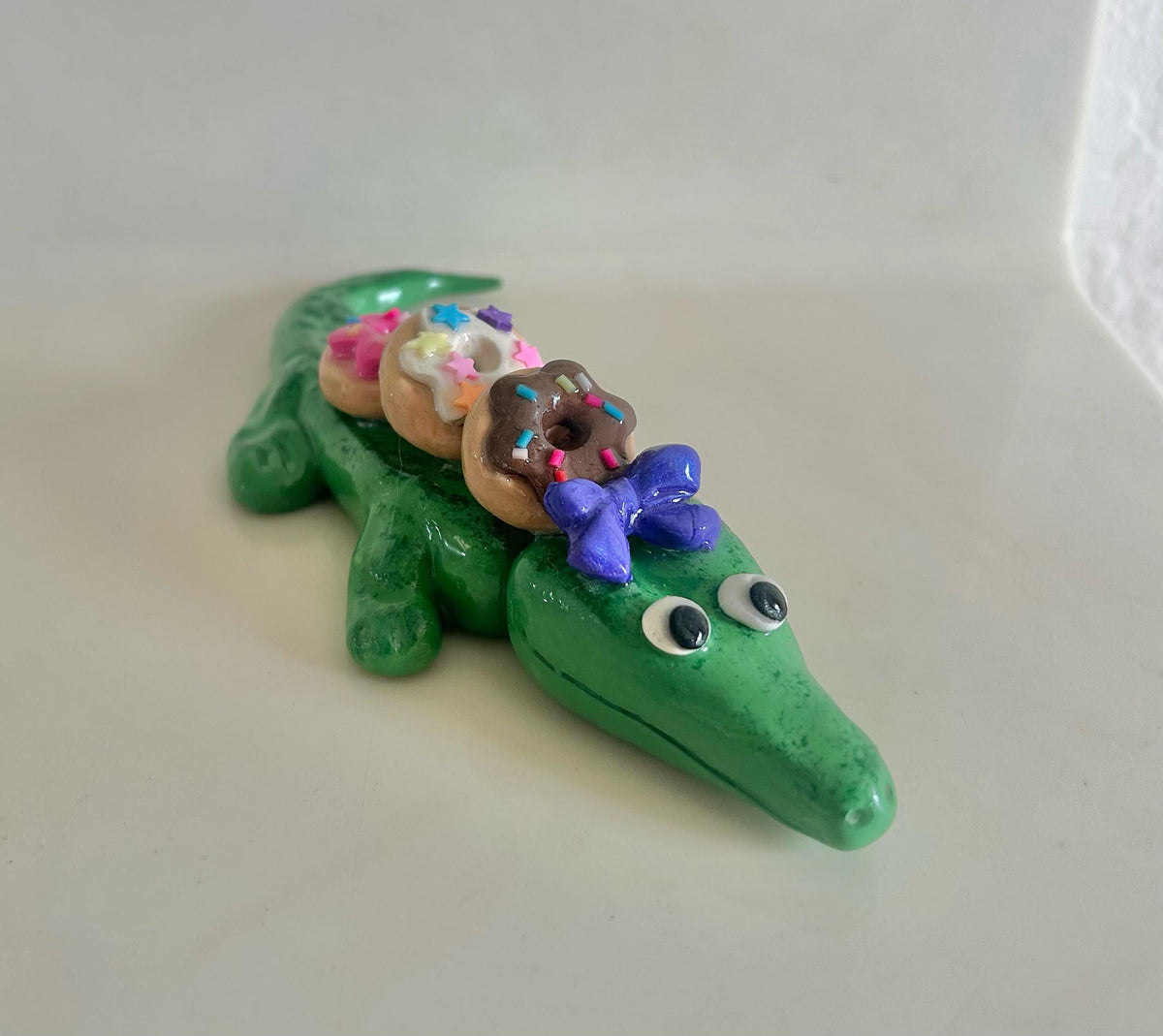 Sculpted alligator figurine with donuts