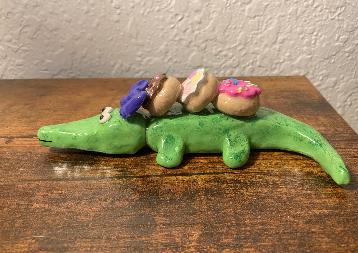 Sculpted alligator figurine with donuts