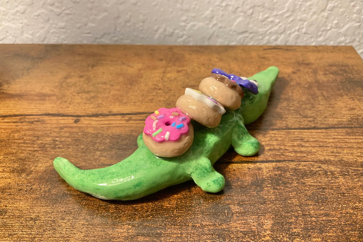 Sculpted alligator figurine with donuts