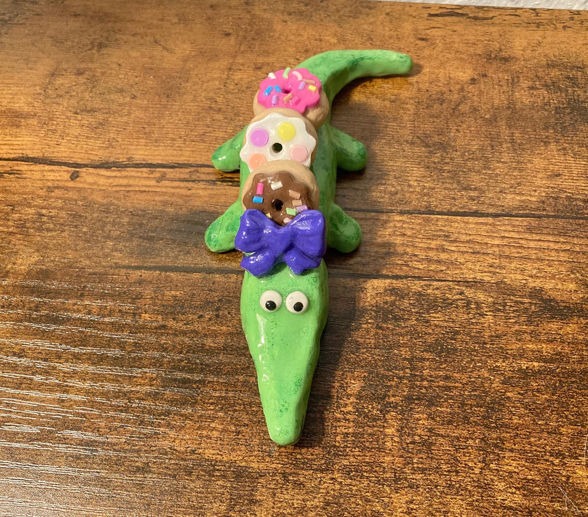 Sculpted alligator figurine with donuts